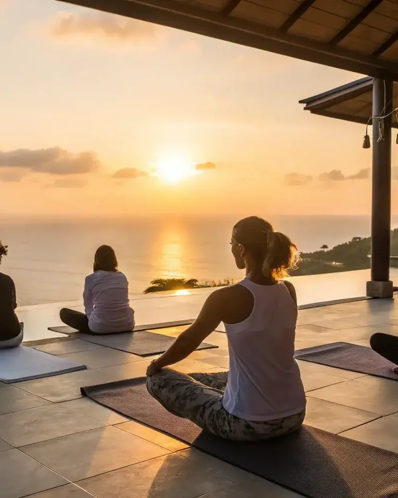 A group yoga session on an open deck as the sun rises over the sea